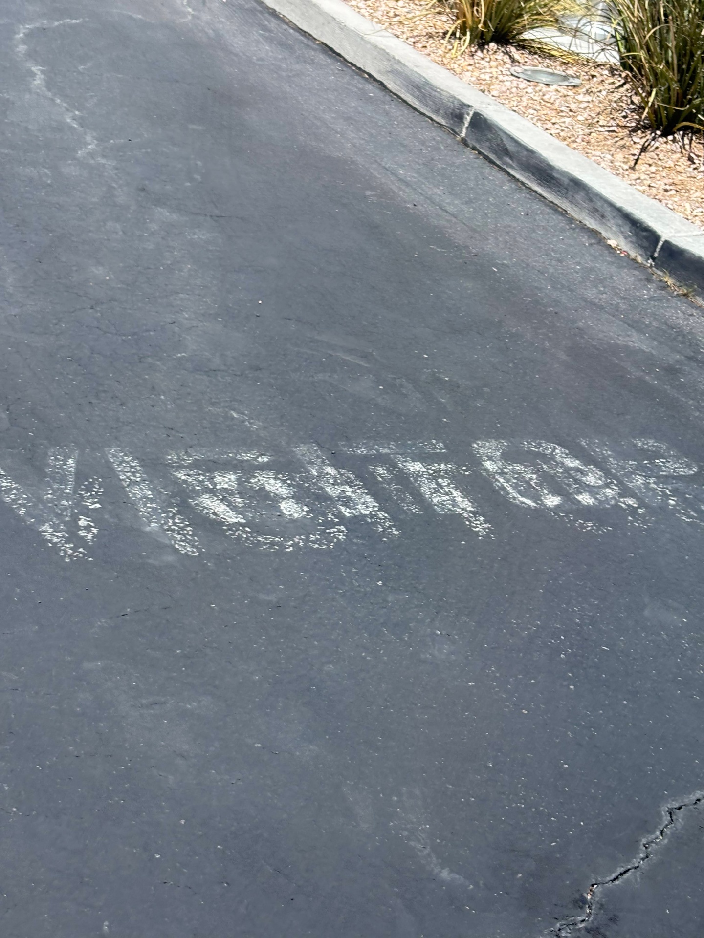 Faded VISITOR text painted on asphalt