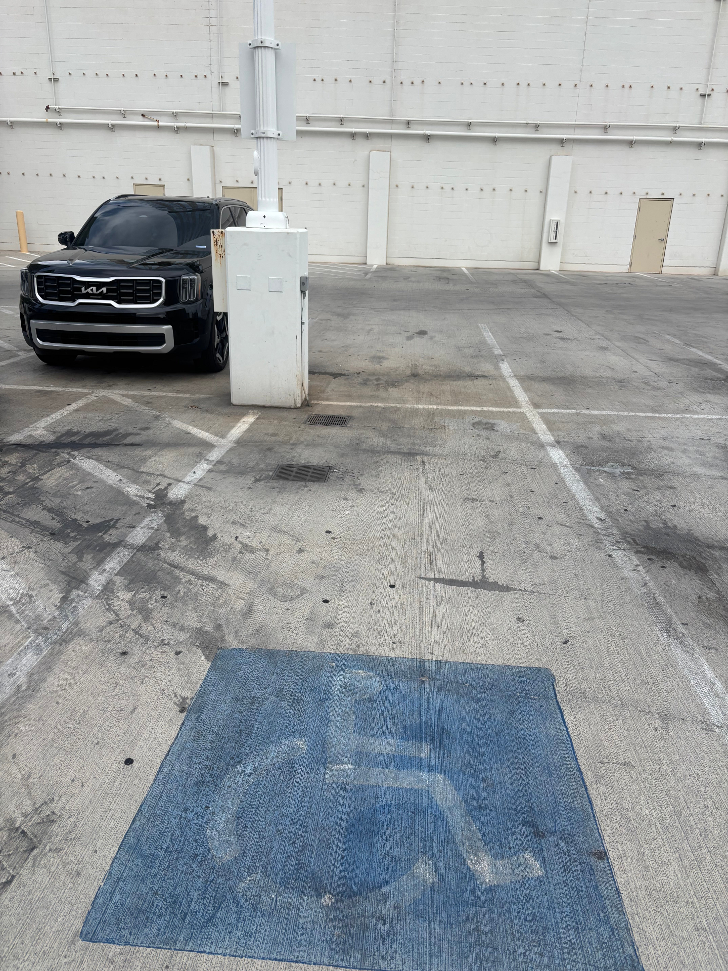 Faded blue accessibility stall in a parking garage with obstruction